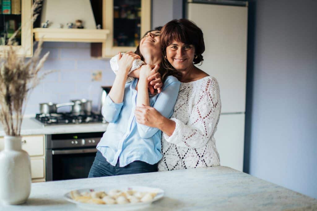 pexels-photo-3893734-3893734 A heartfelt embrace between mother and daughter in a cozy kitchen setting.